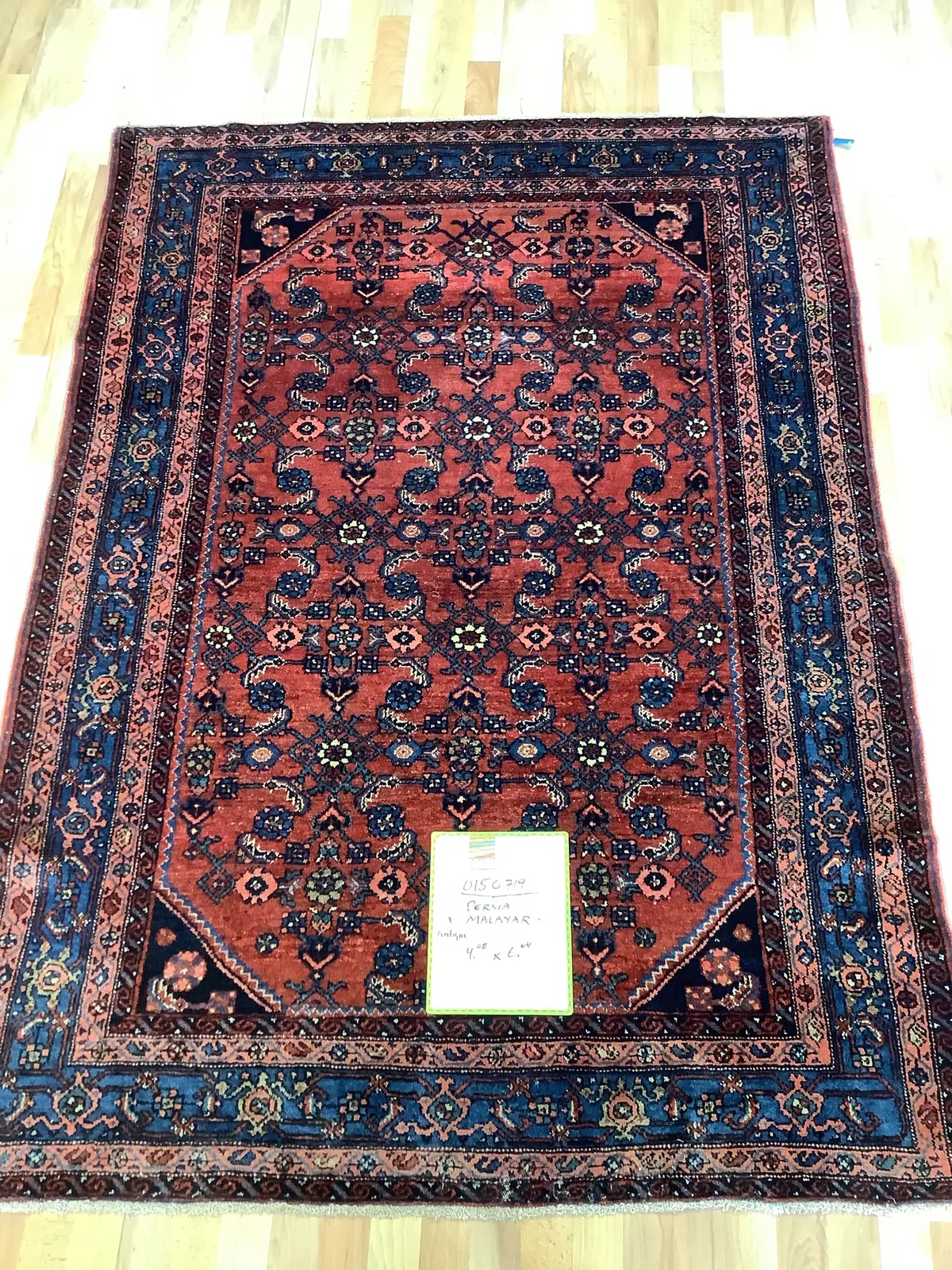 Vintage Persian Malayer rug with a red field, navy borders, and ivory floral motifs, laid flat at Oriental Rug Works in Keene, NH